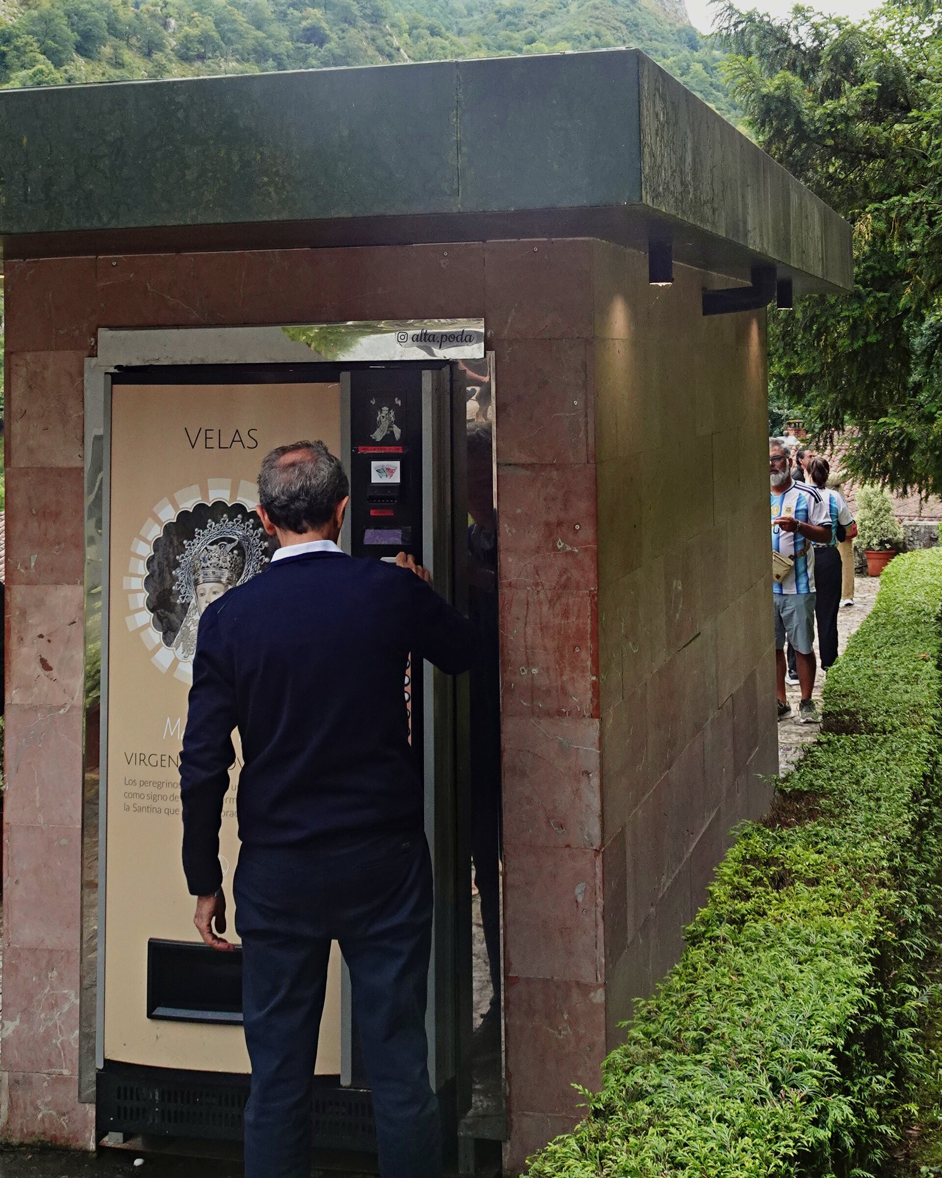 A man buying candles from a vending machine at a mountain sanctuary