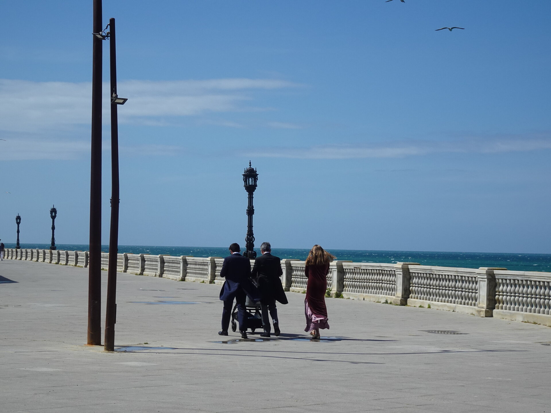 People walking along a seafront promenade toward the sea