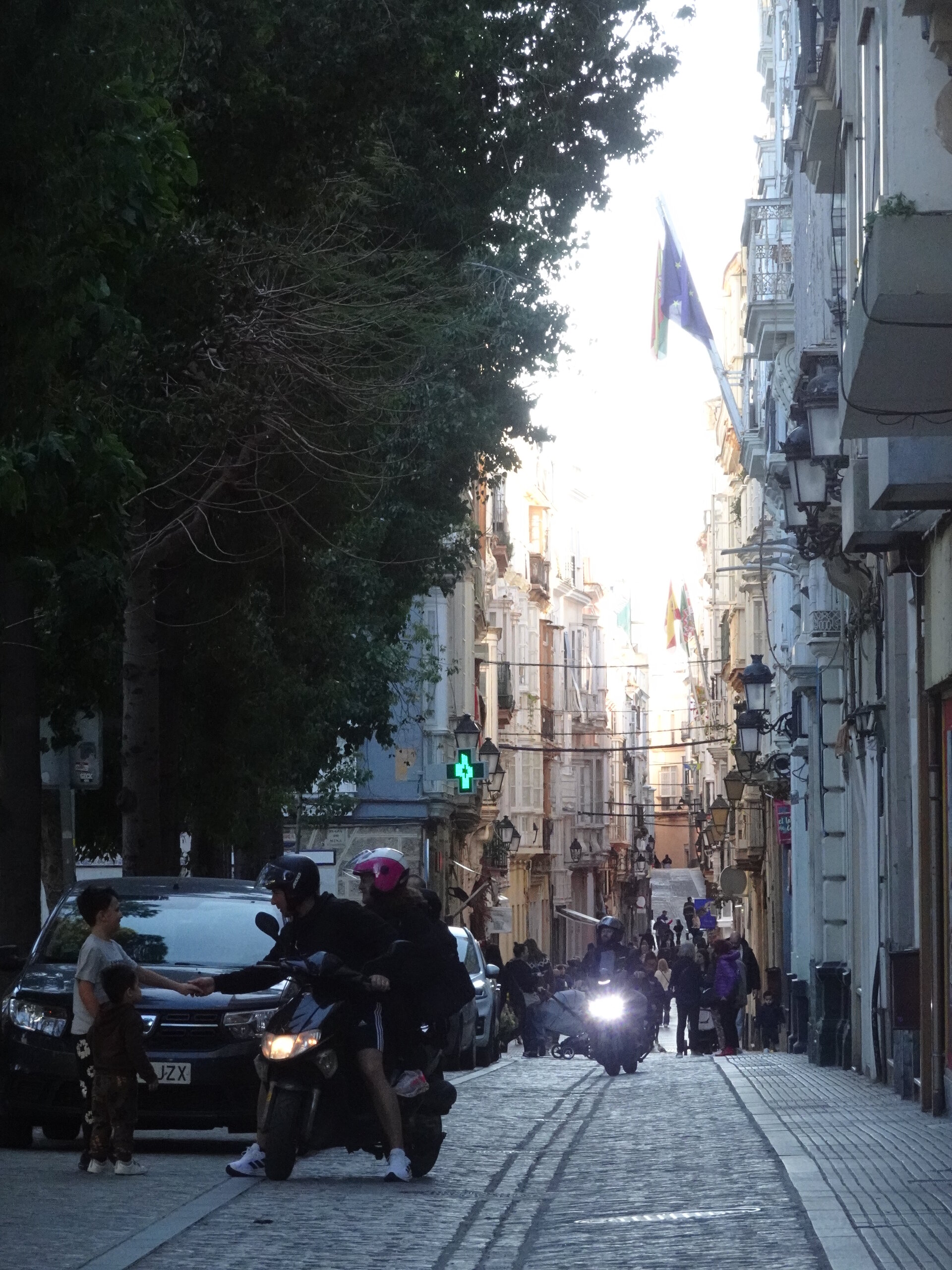 Scooters on a narrow street with evening light between buildings