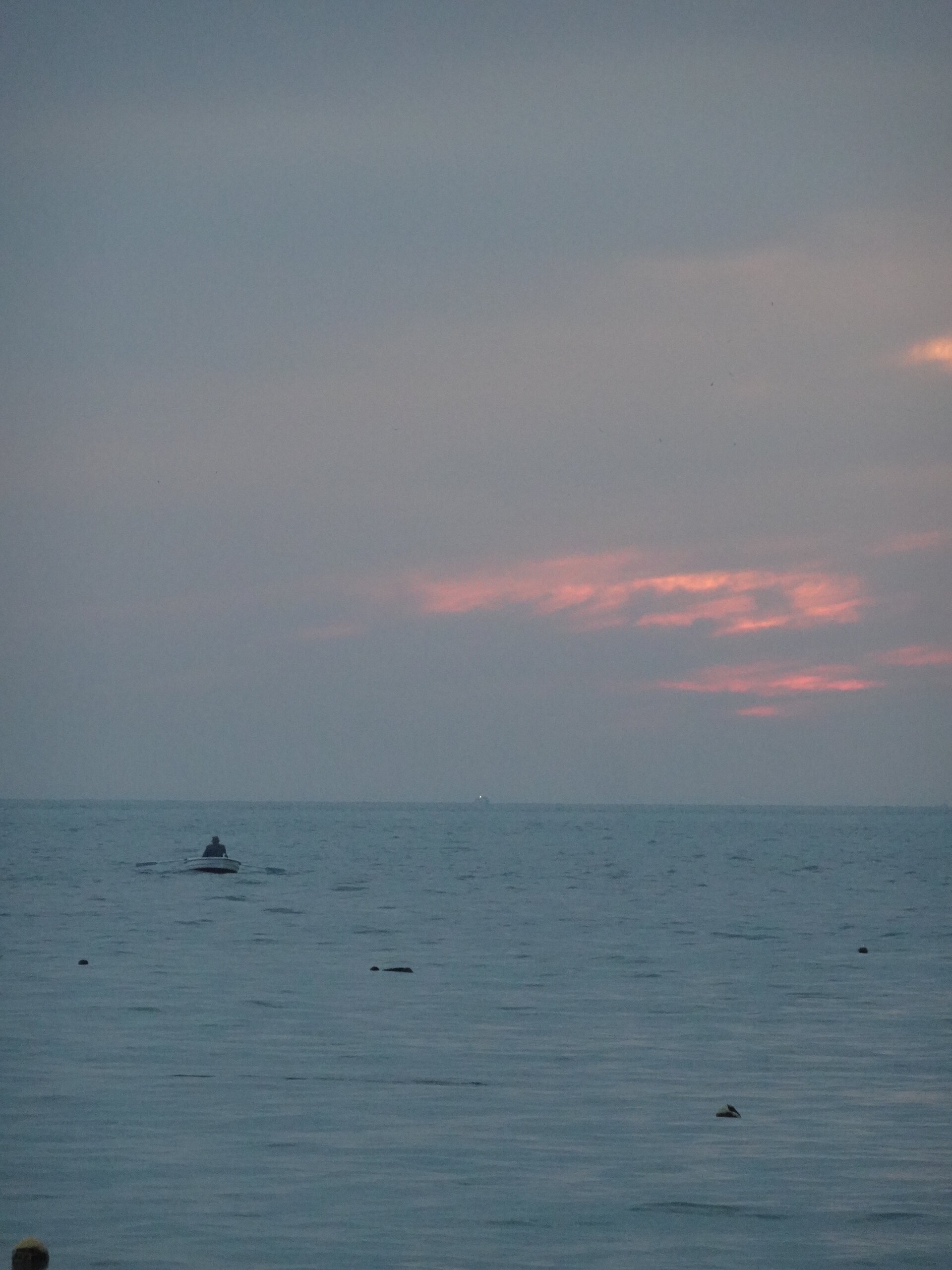 Calm sea under pink-tinged clouds at dusk
