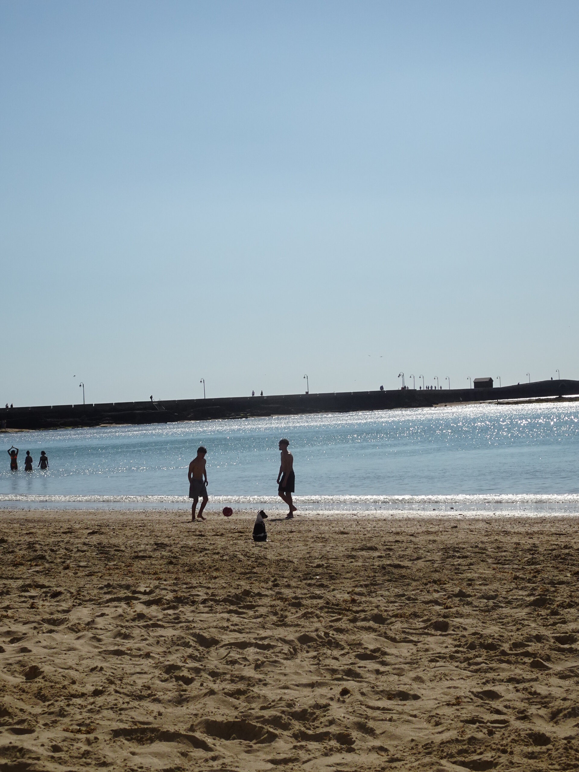 Two people on a sandy beach with sparkling blue sea