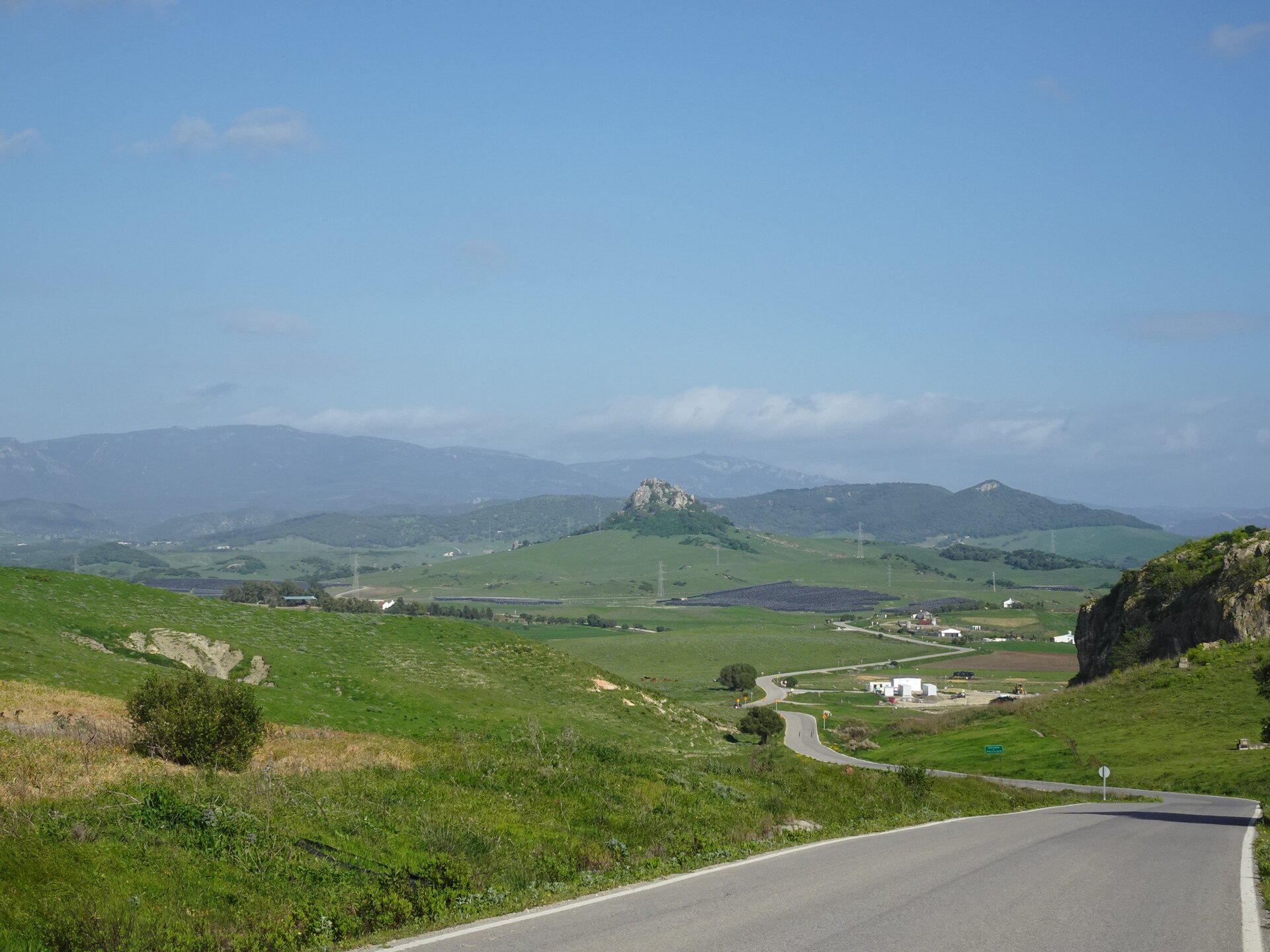 Winding road through green rolling hills with a rocky outcrop