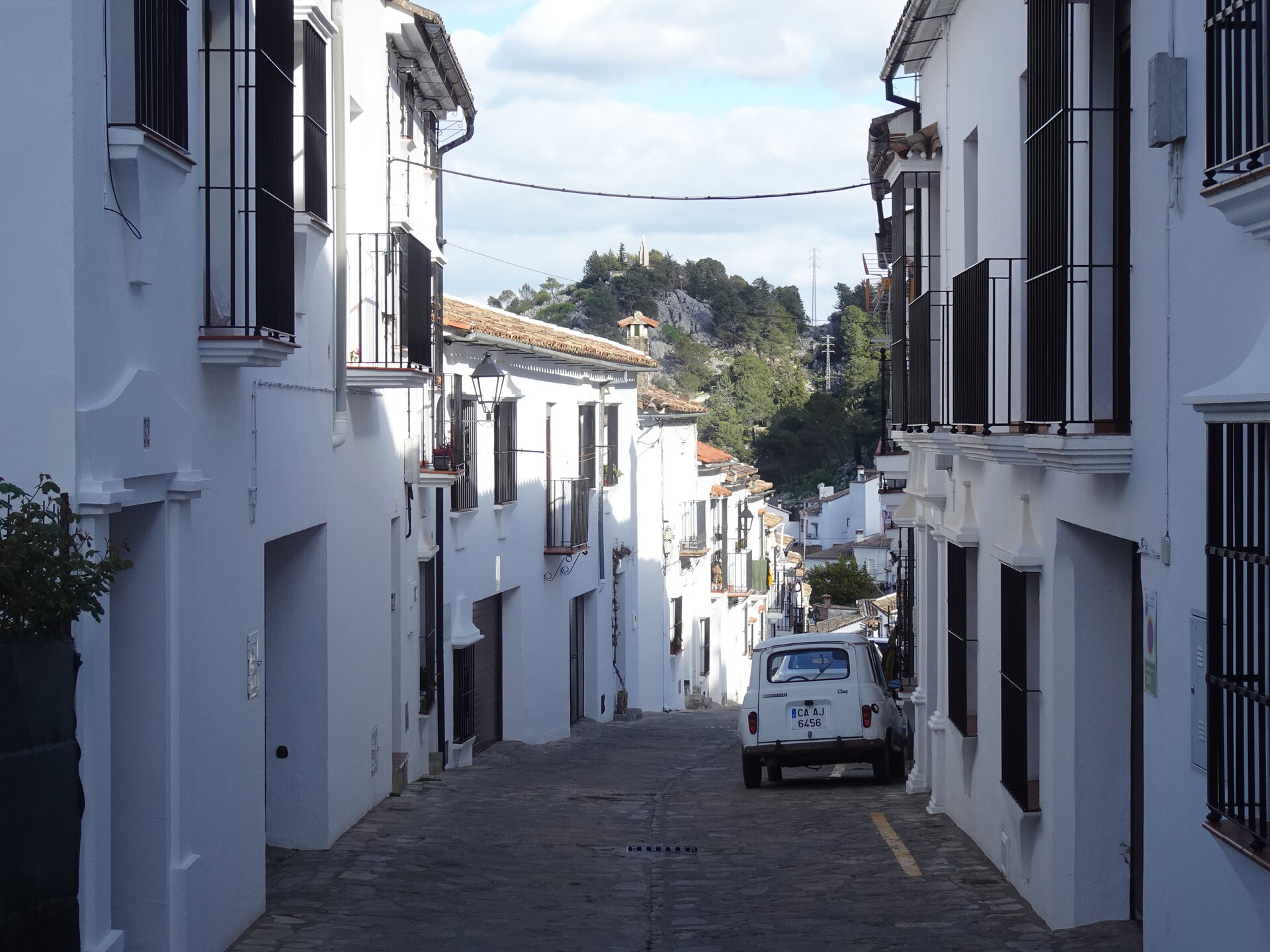 White-washed street with a hilltop castle beyond