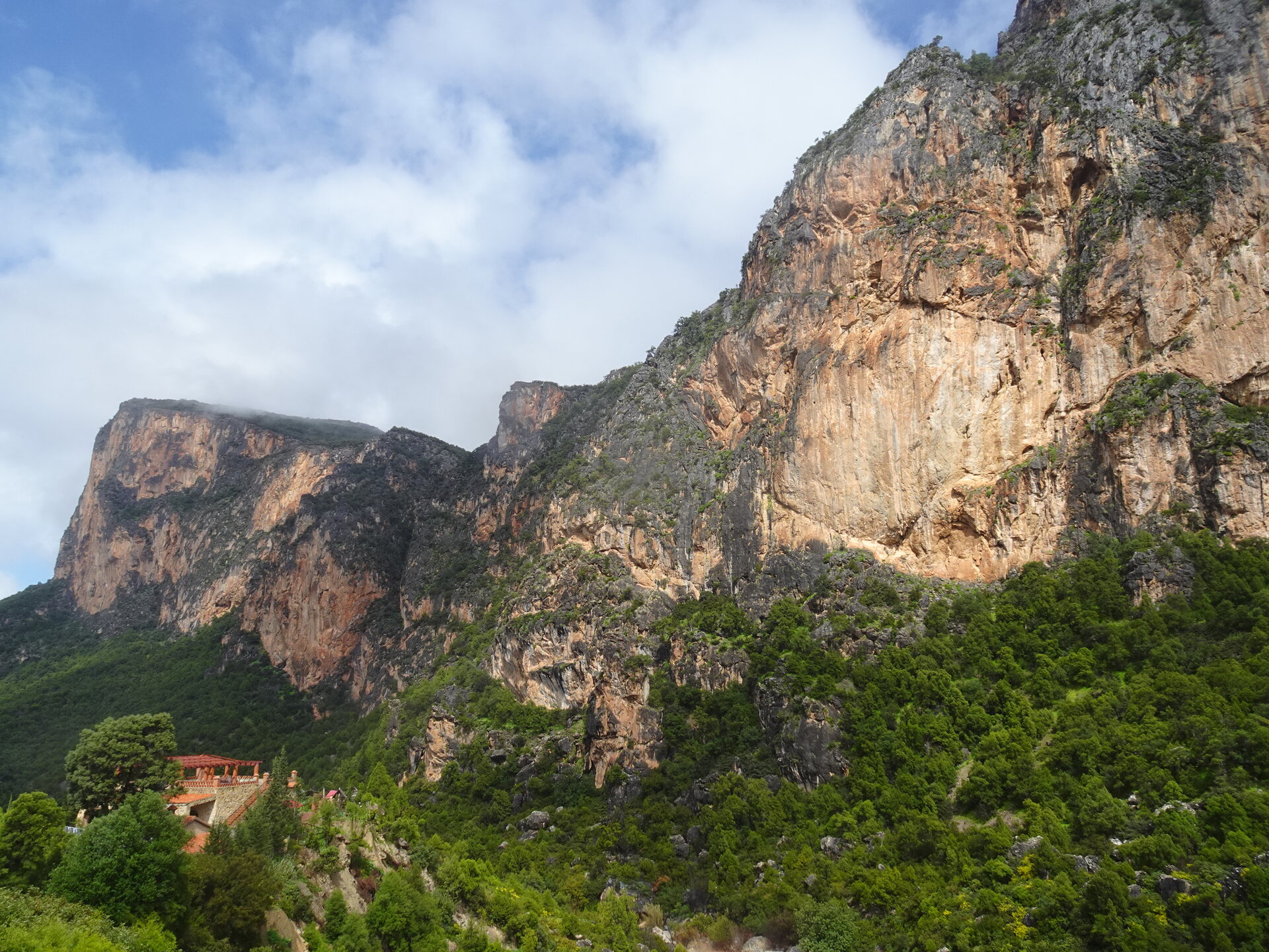 Towering limestone cliffs with a small building nestled at their base