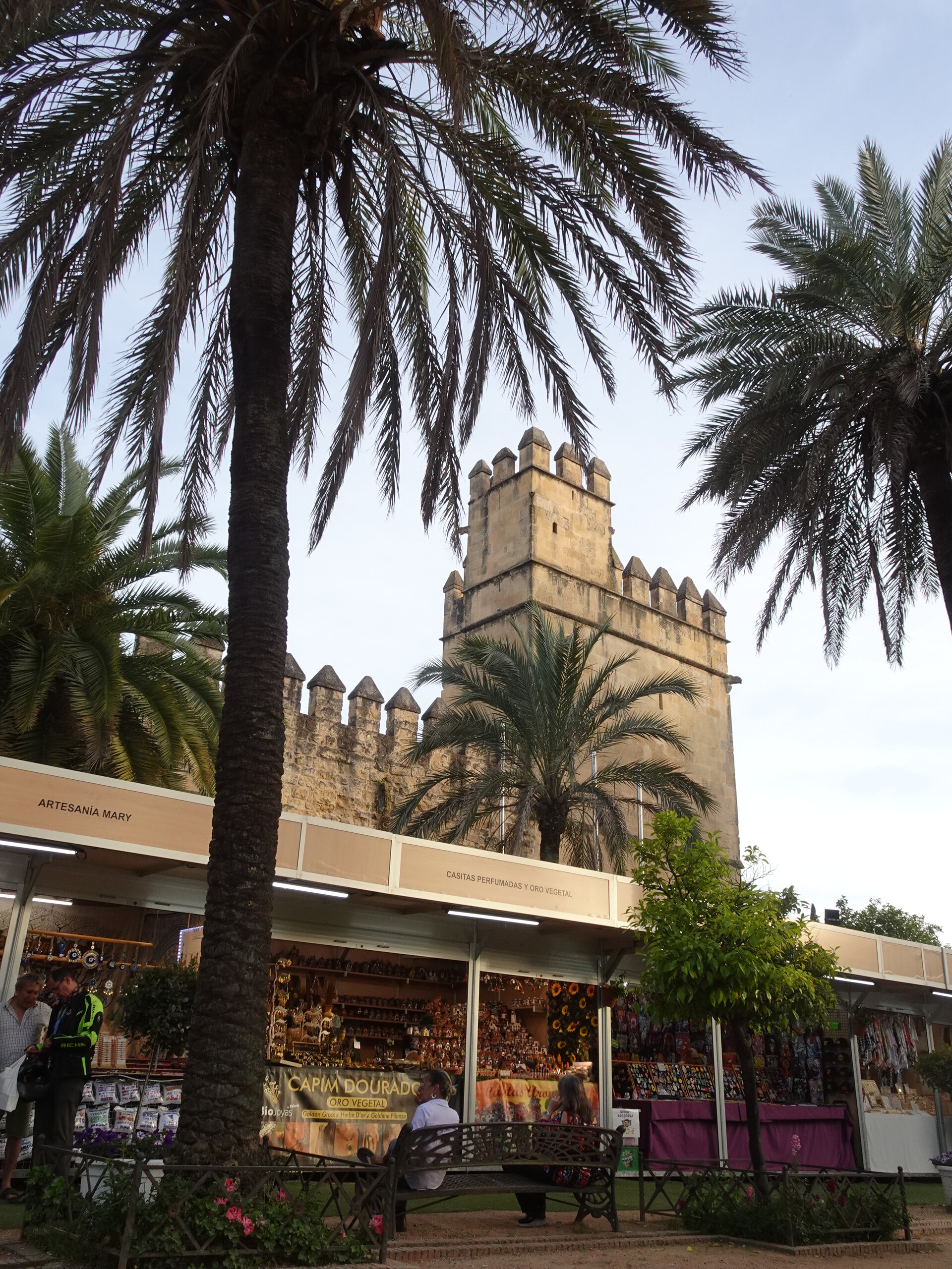 Crenellated fortress tower framed by palm trees above a row of market stalls