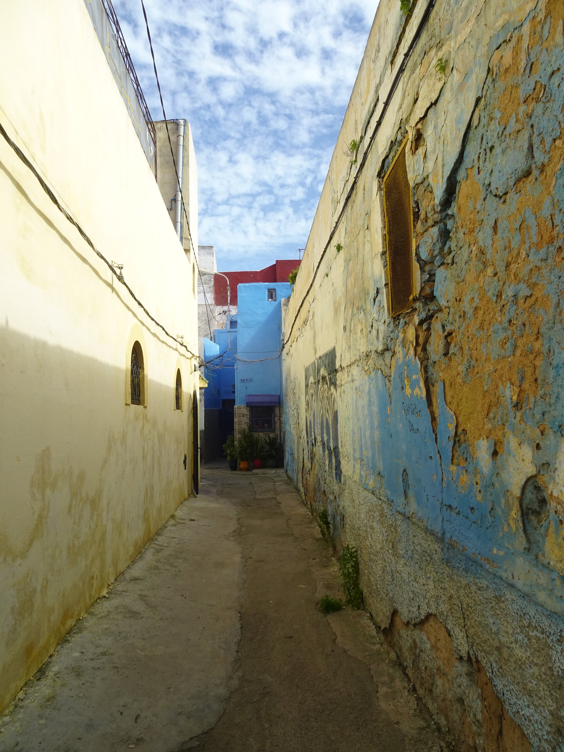 Narrow alley with peeling yellow and blue painted walls in the Portuguese city
