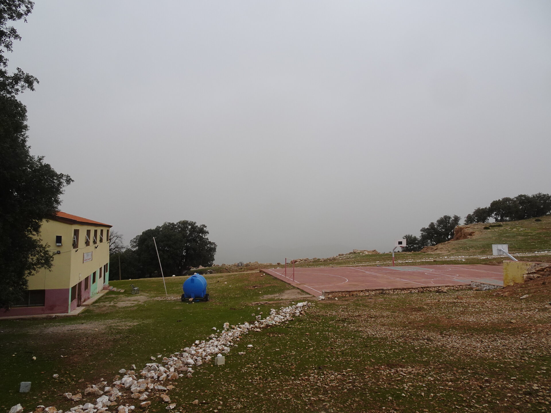 School building and basketball court on a misty hilltop