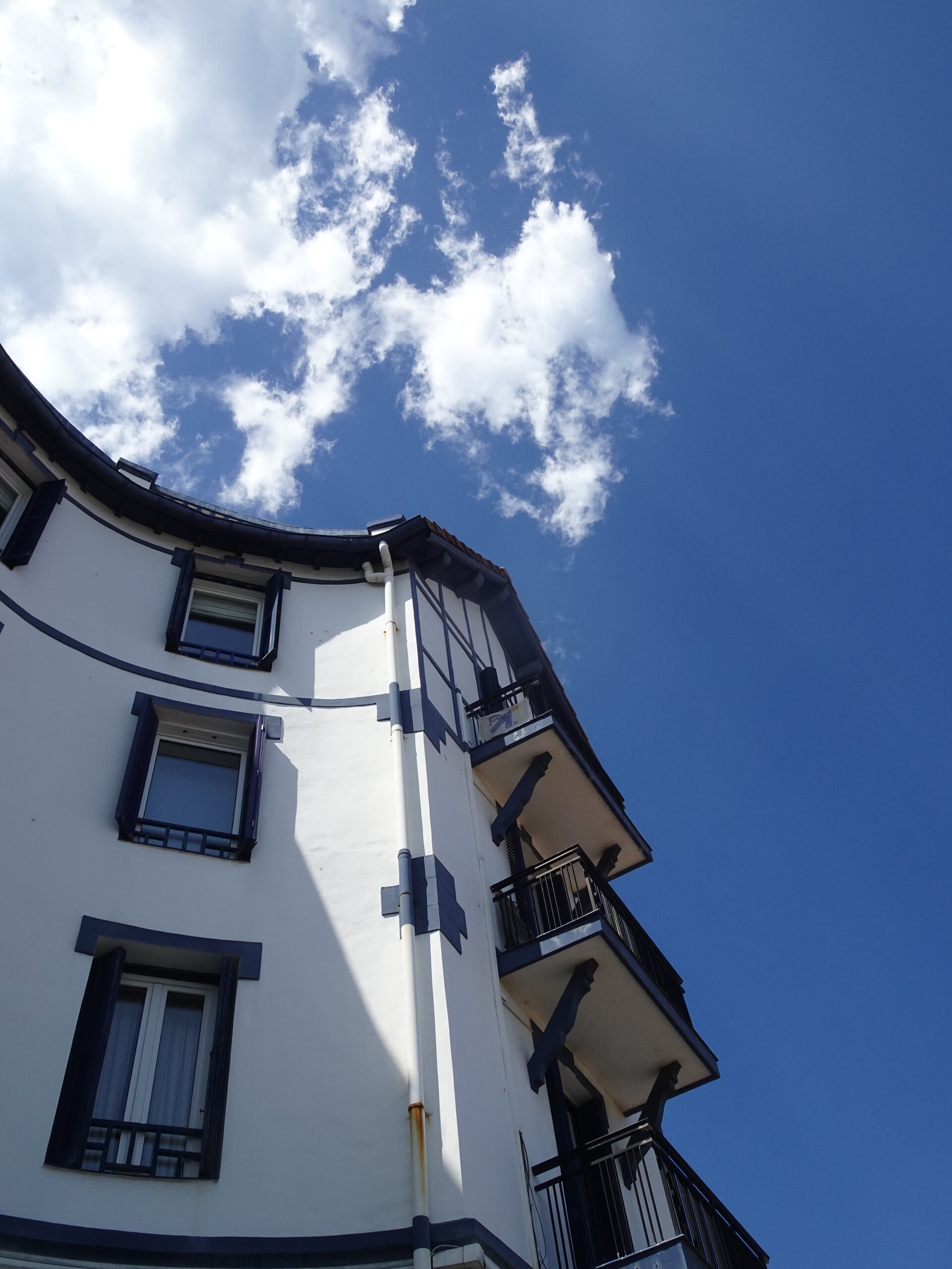 Looking up at a white half-timbered building against a deep blue sky