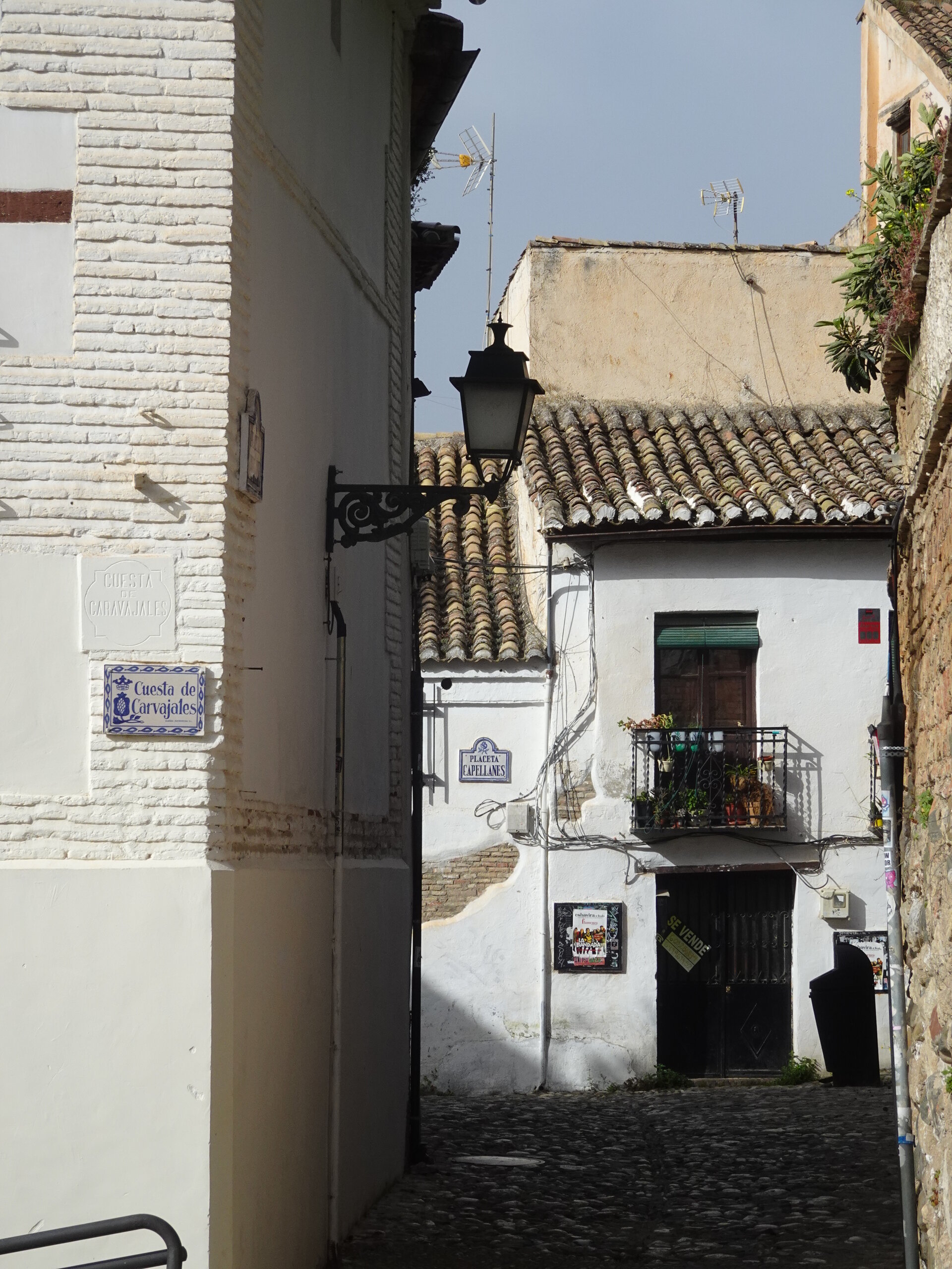 Whitewashed alley in the Albayzin with a wrought iron lantern and tiled street sign