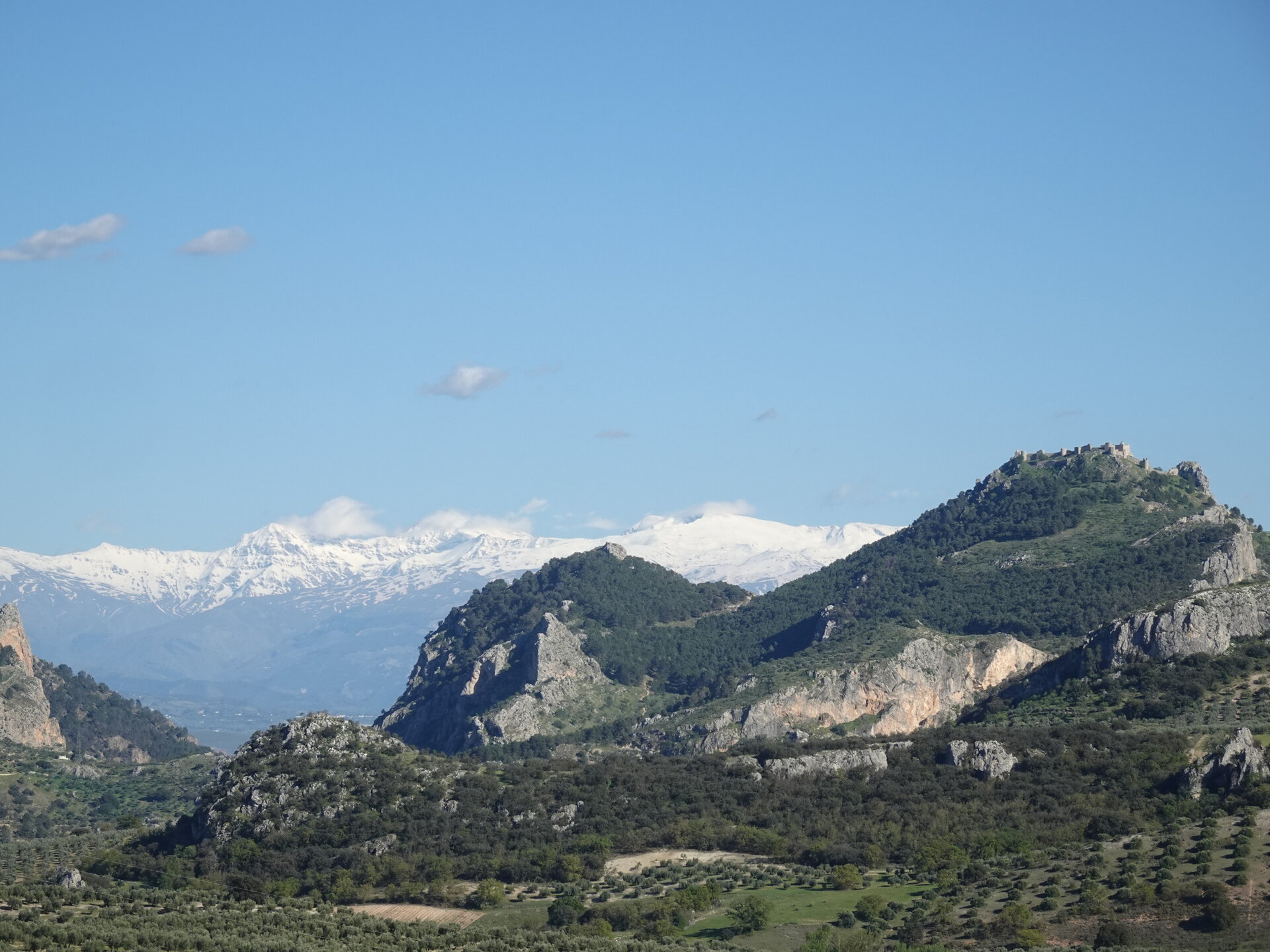 Rocky outcrop with castle ruins and the snow capped Sierra Nevada beyond