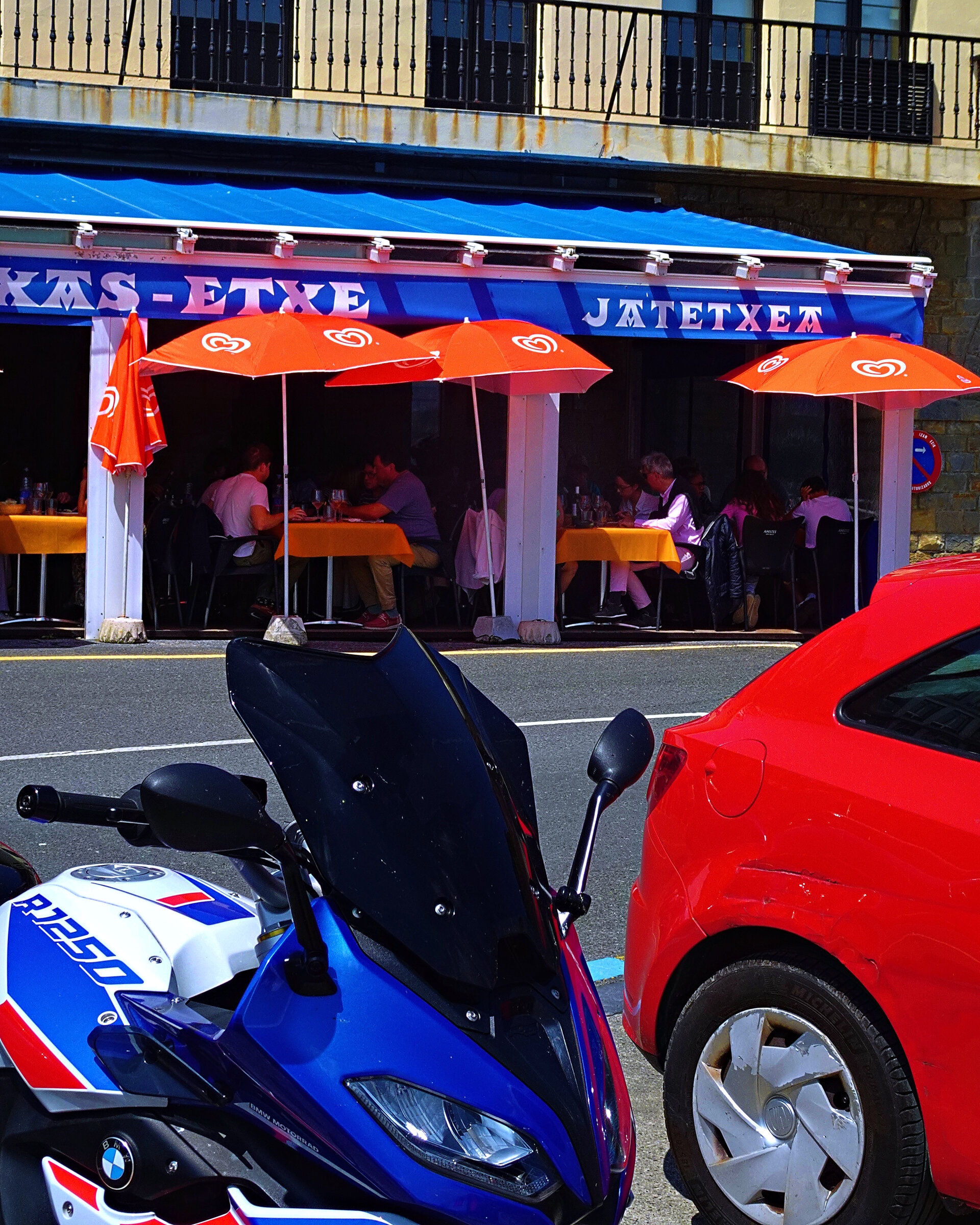 Orange parasols shading a busy harbourside restaurant terrace