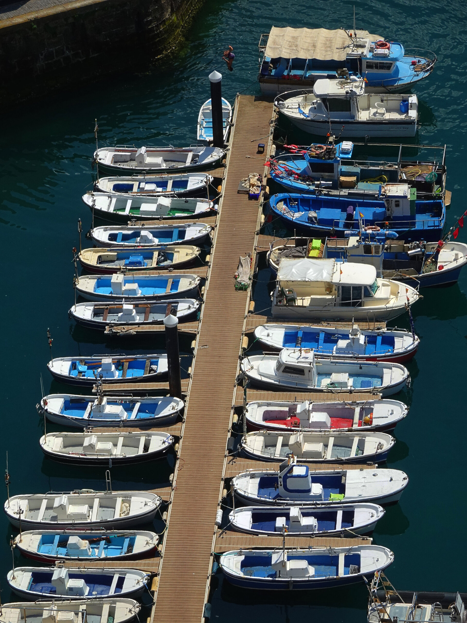 Rows of small fishing boats moored along a wooden jetty