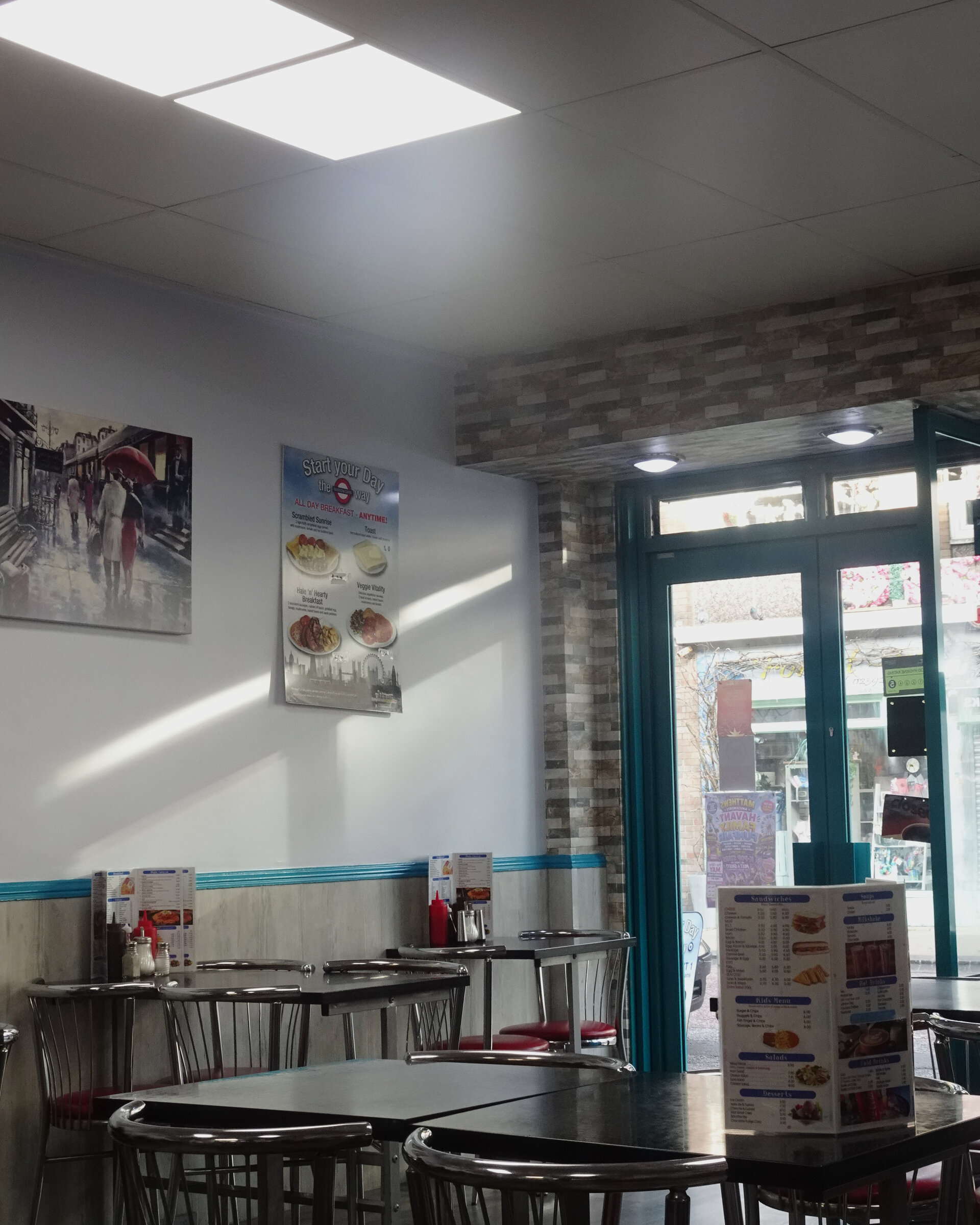 A bright café interior with tables and chairs beside a sunlit window