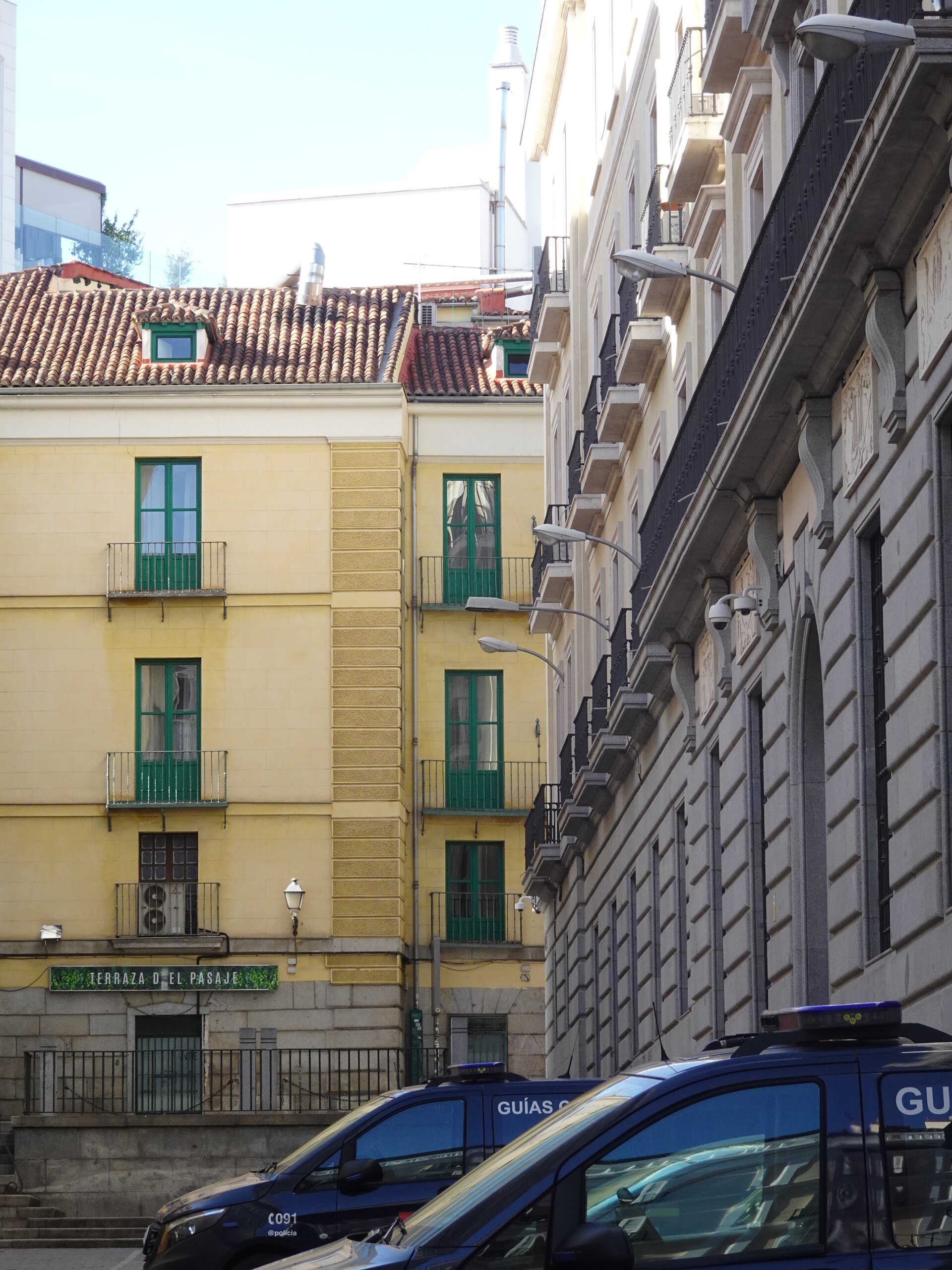 Yellow apartment building with green shutters beside parked police vans