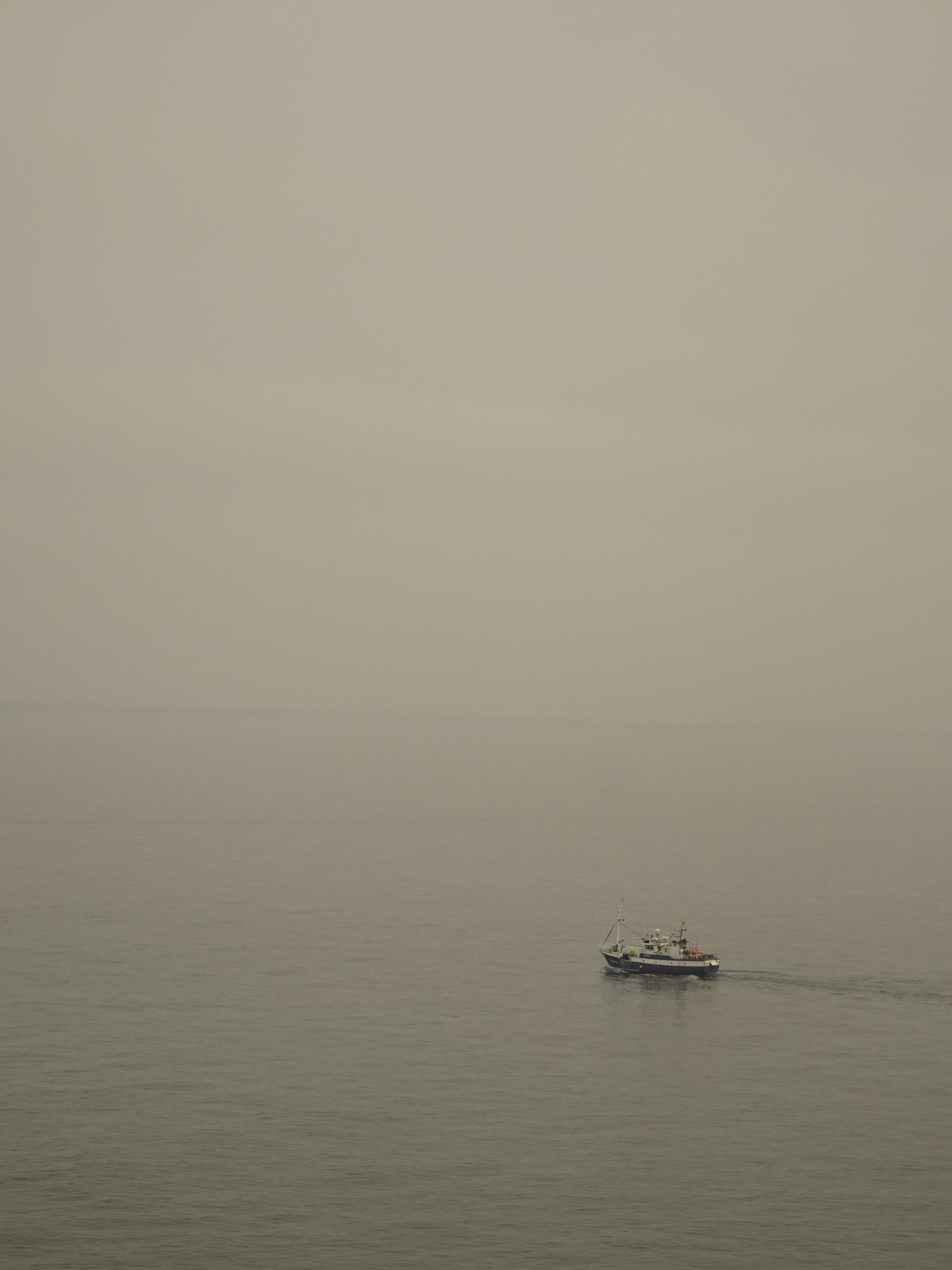 Two fishing boats on a hazy, calm grey sea