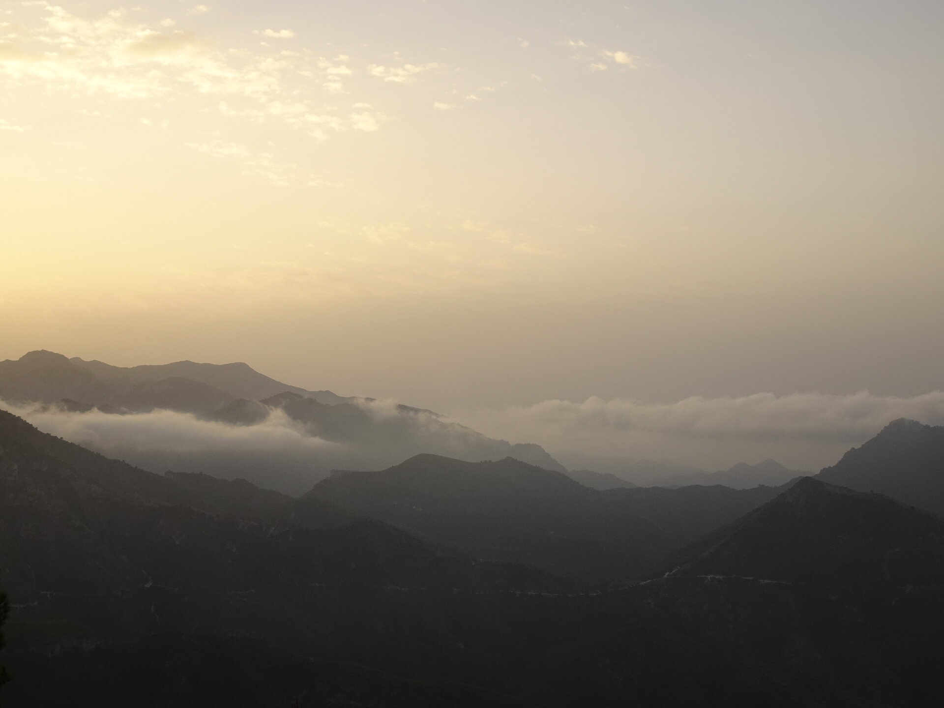 Layered mountain silhouettes with mist in the valleys at sunrise