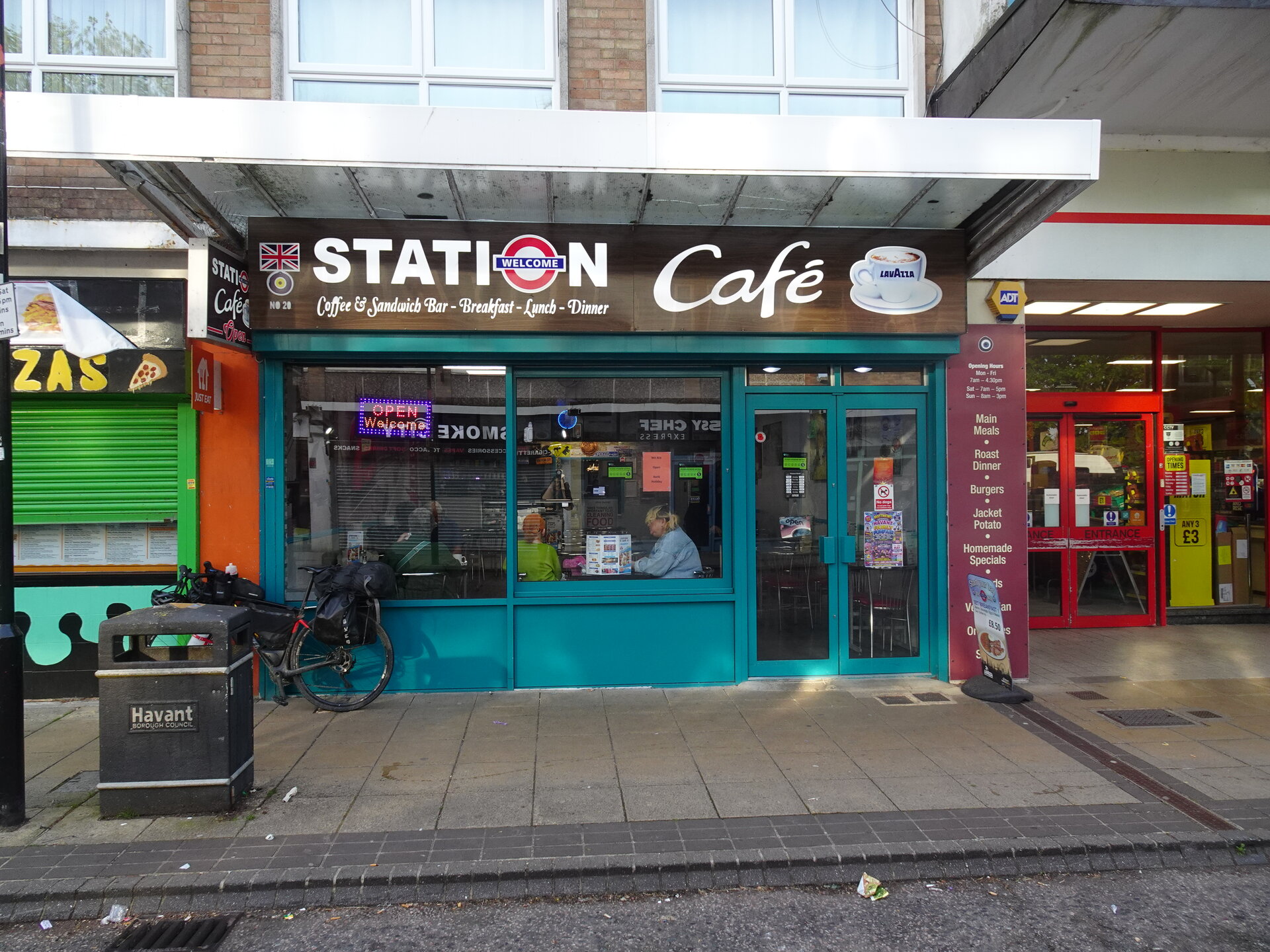 A teal-fronted Station Café on a high street with a bike parked outside
