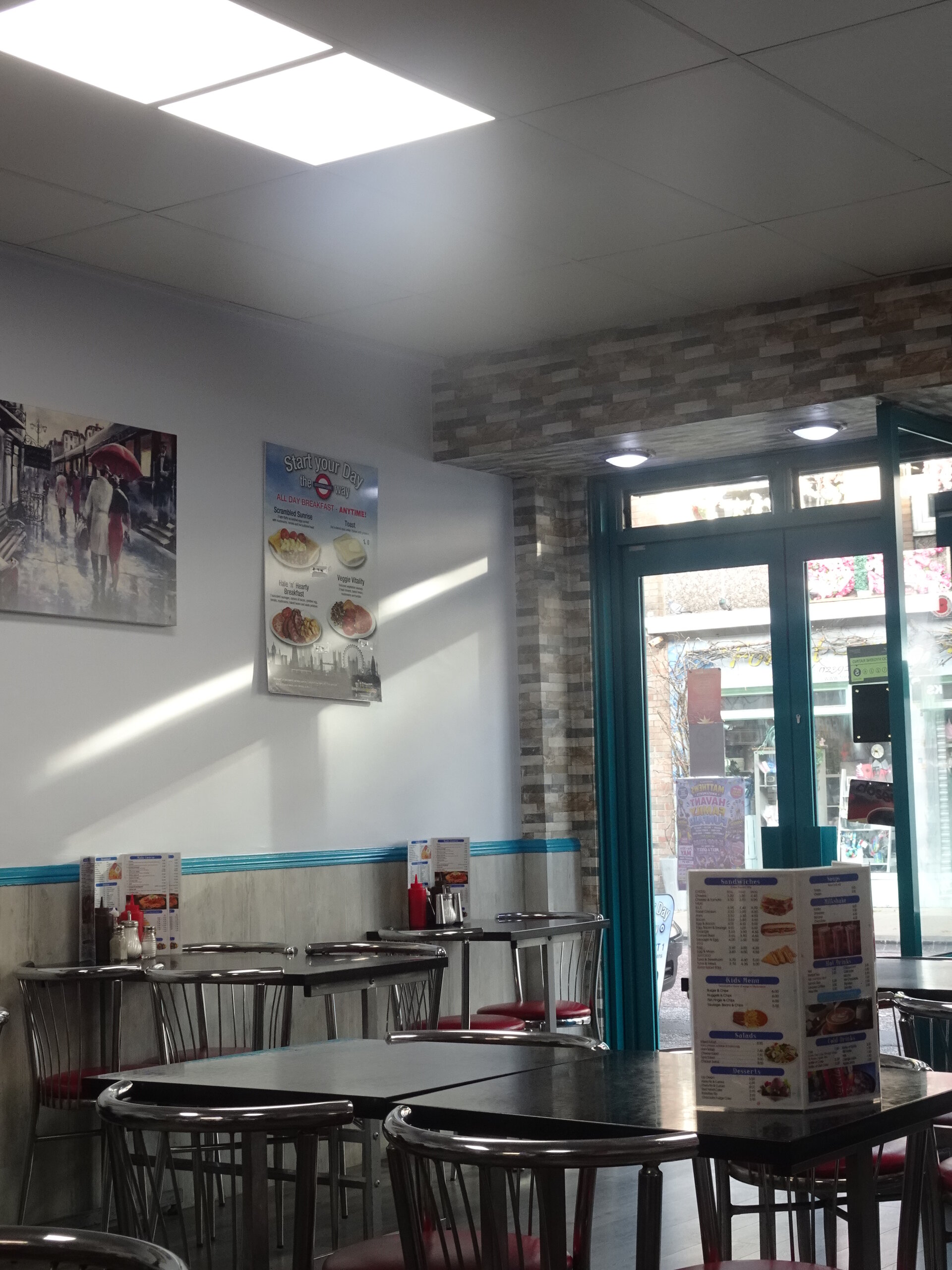 Empty tables inside a bright café looking out to the street through open doors