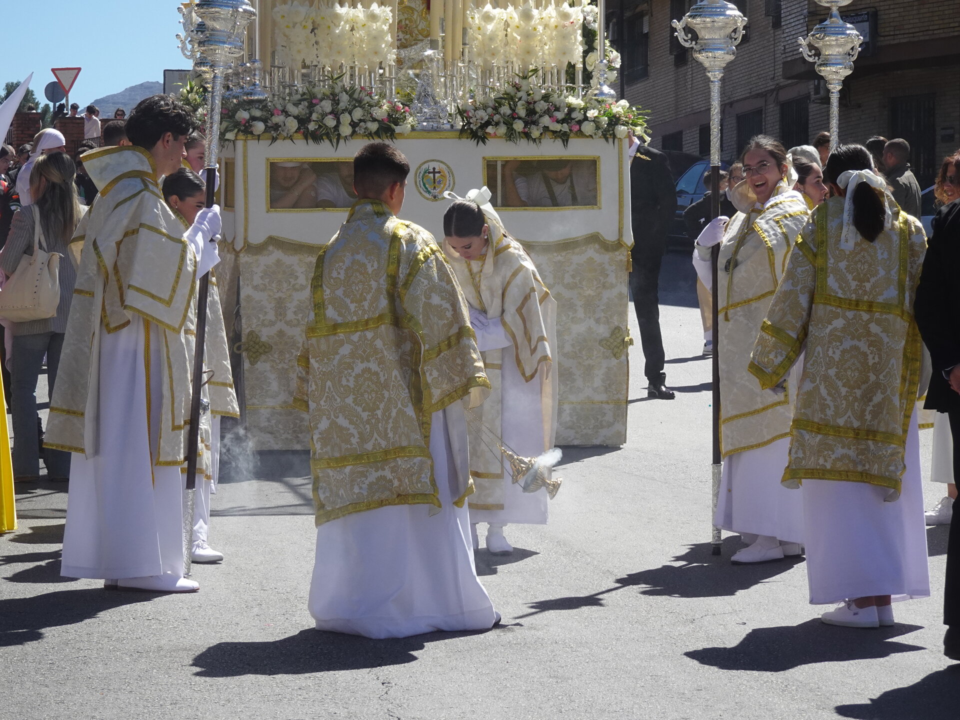 Altar bearers in gold and white robes carrying a float