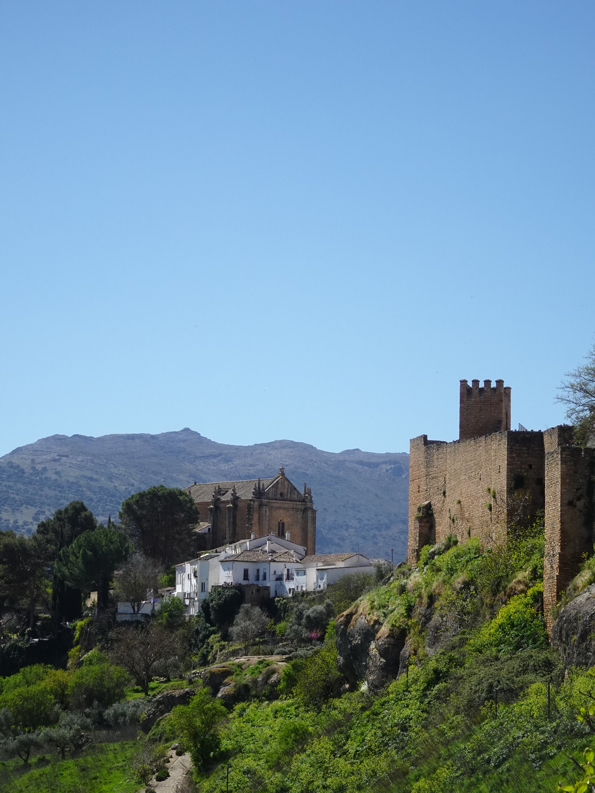 Church and fortress walls on a clifftop with mountains behind