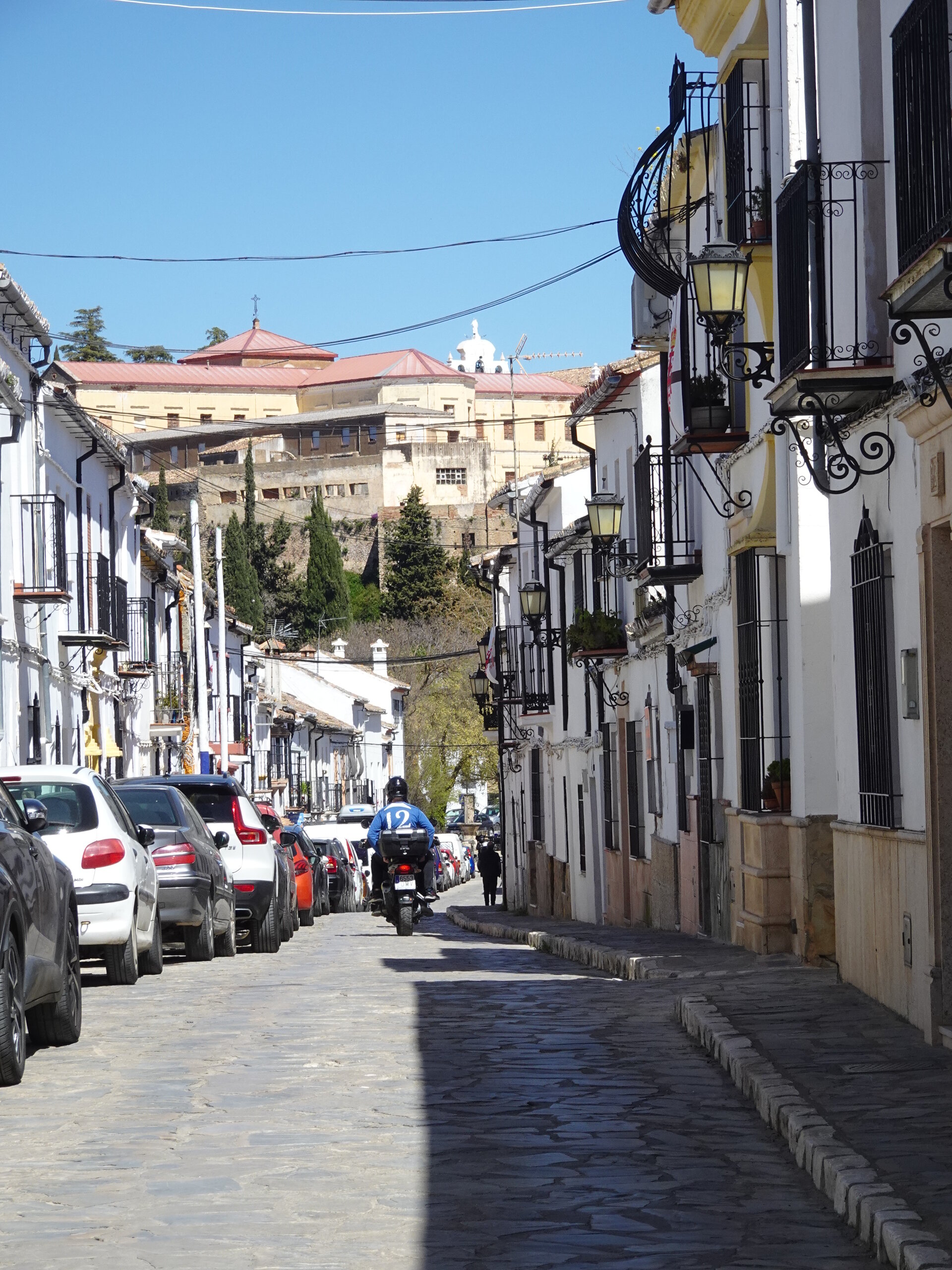 Cobblestone street with balconies and a scooter rider