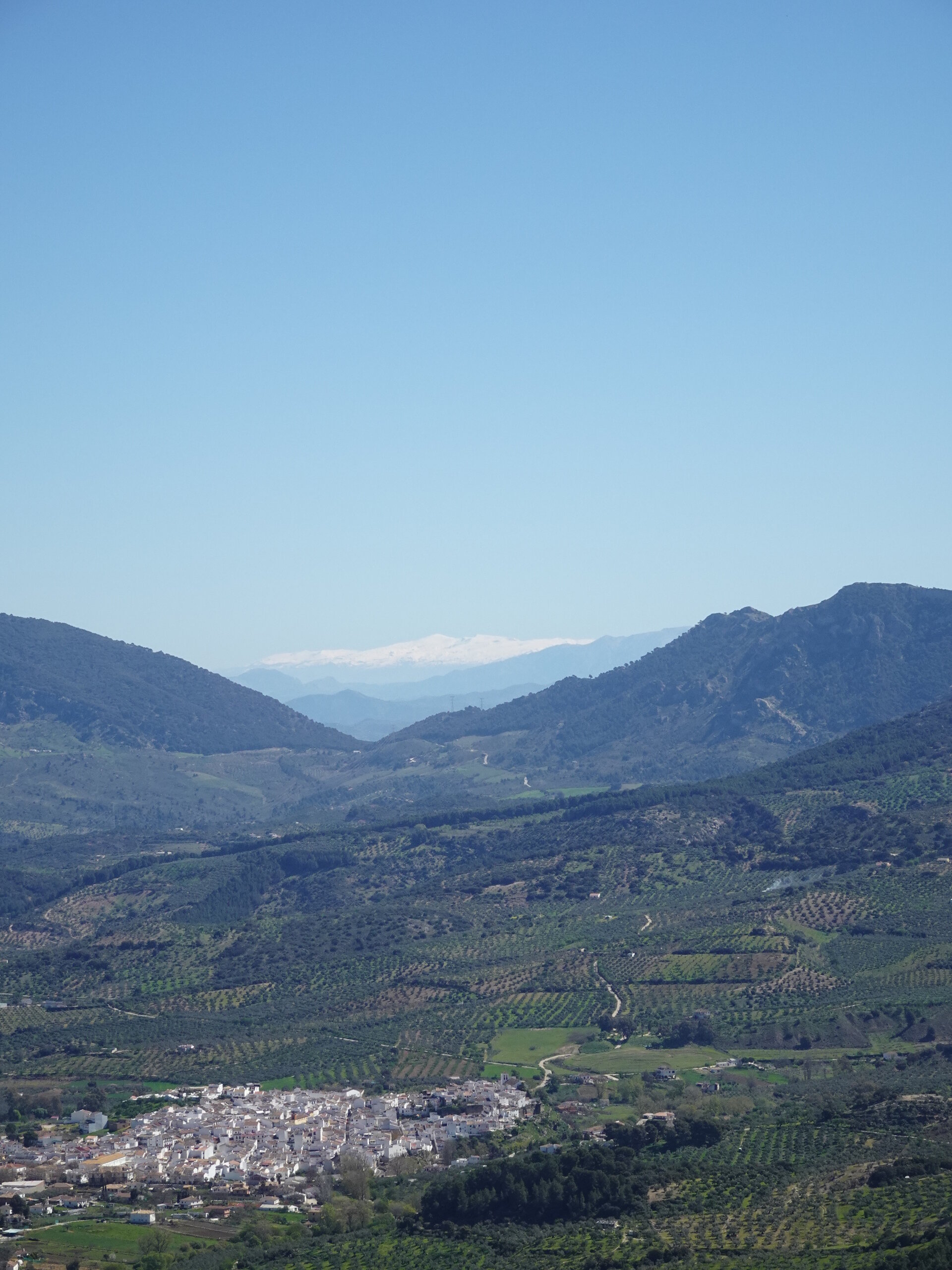 White statue in a valley with snow-capped mountains beyond
