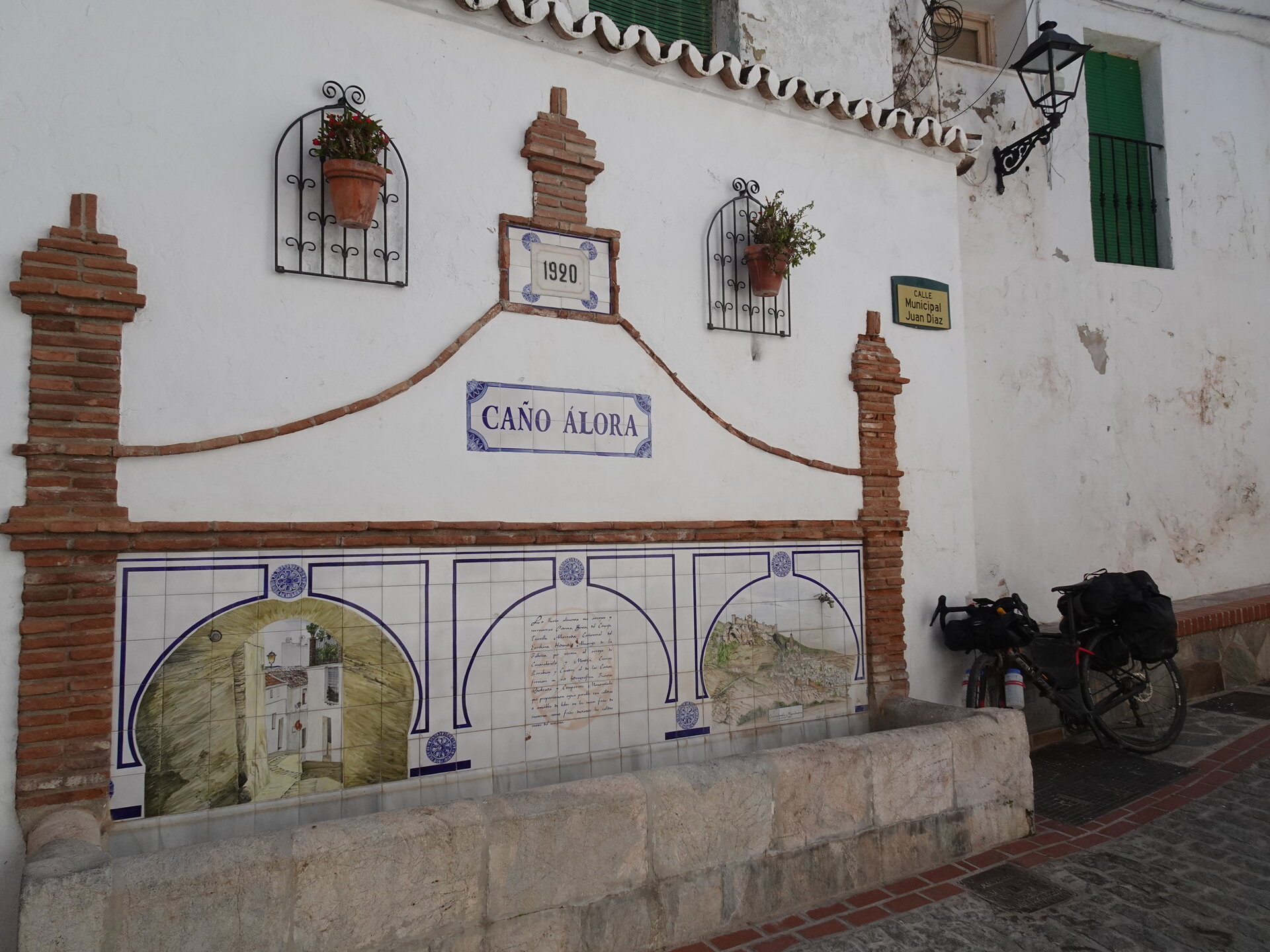 Tiled fountain and touring bike in a white village square