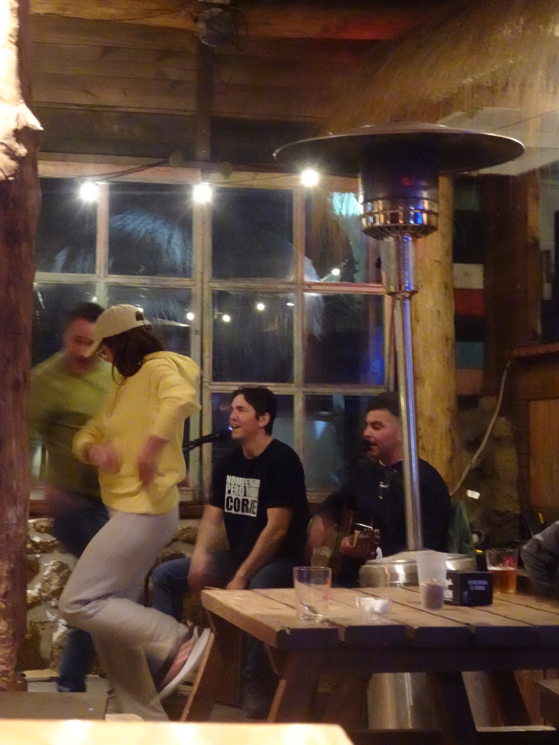 Friends laughing at an outdoor bar with string lights at night