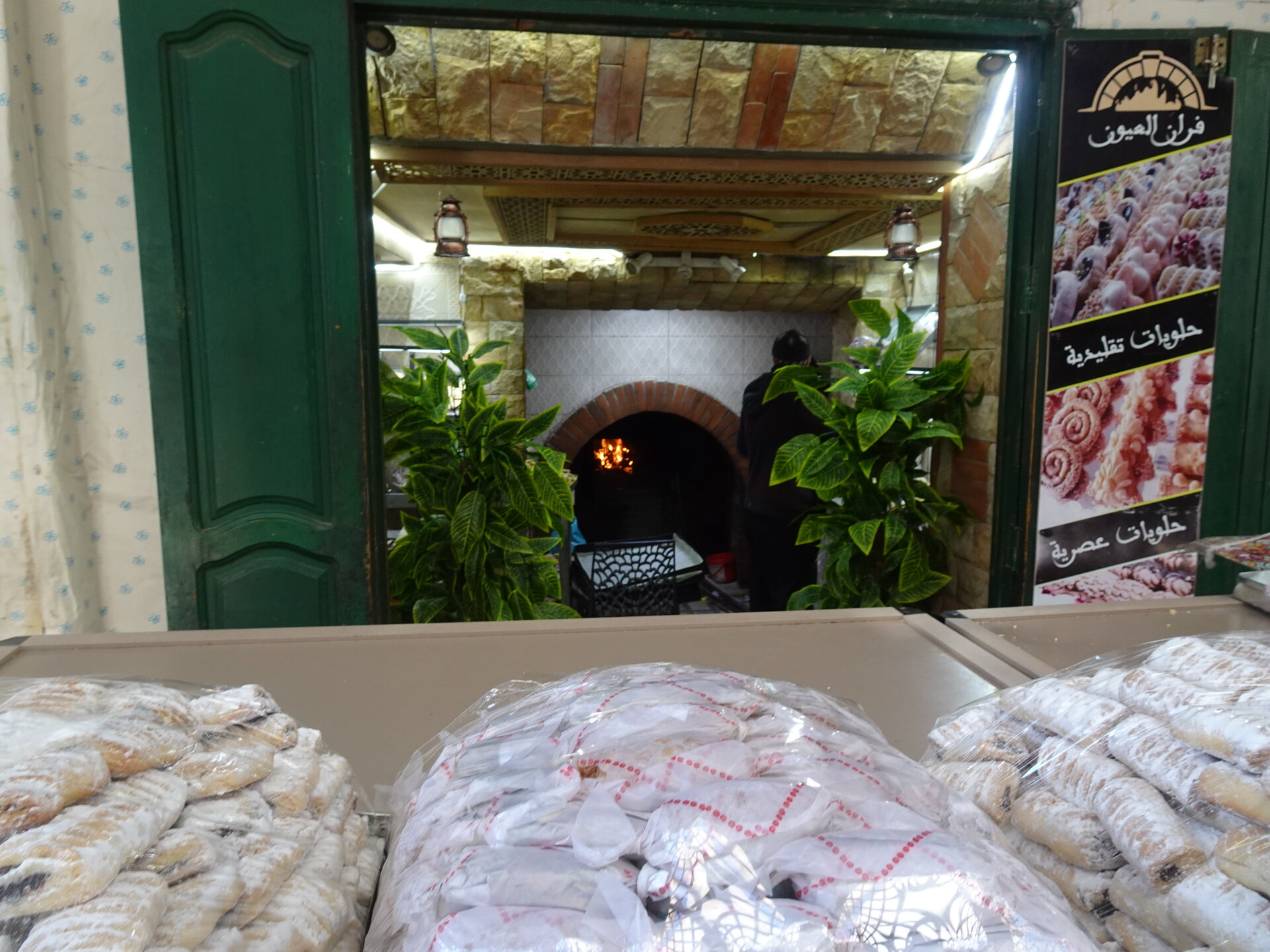 Bakery with pastries on display and a wood-fired oven glowing inside