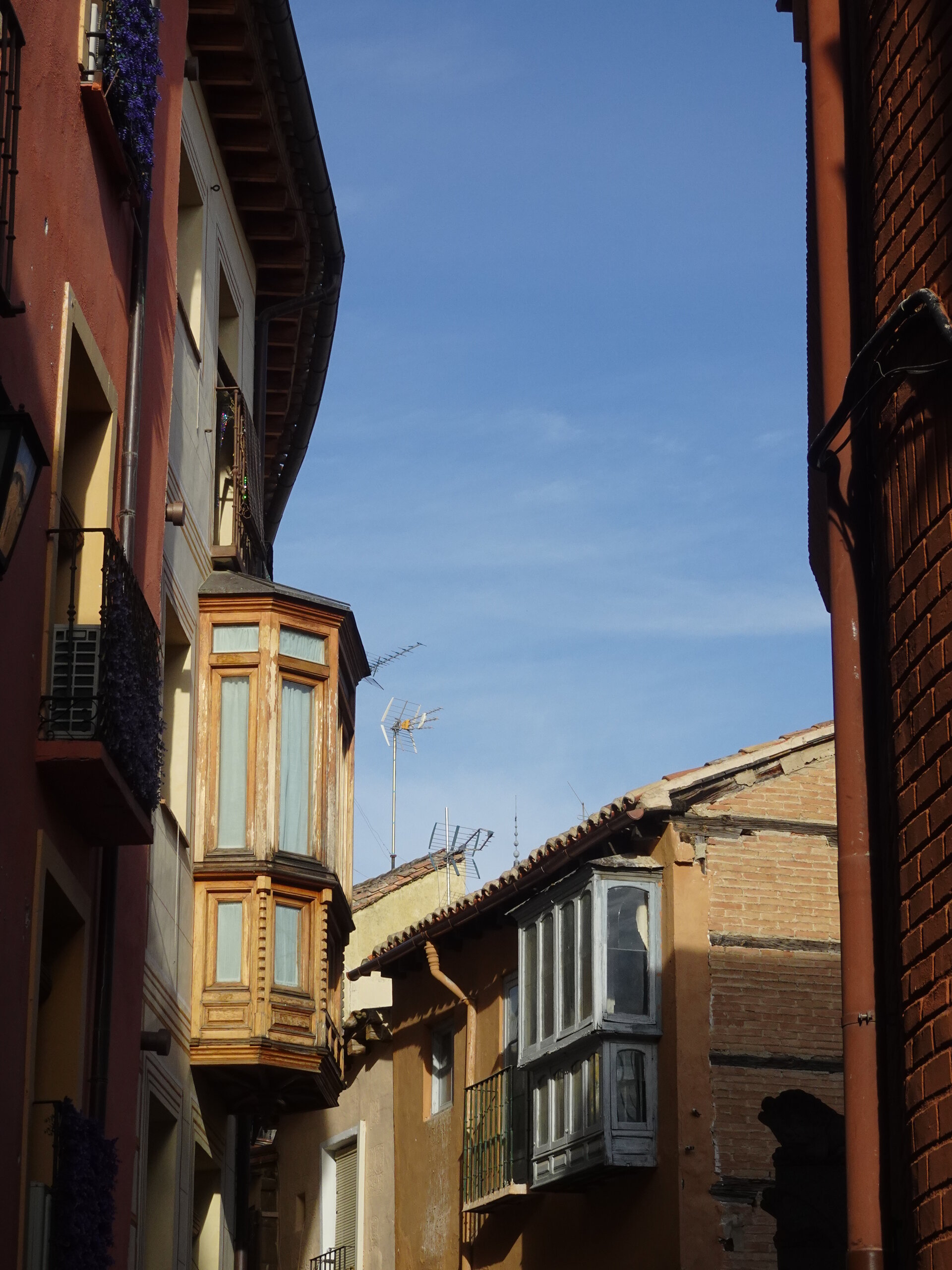 Wooden bay window jutting from a red brick facade in a narrow Toledo street